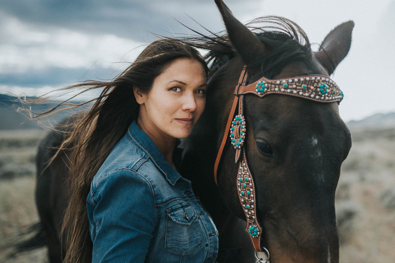 native canadian photographer candice camille stands with her horse and her hair blowing in the wind in this gorgeous image by horse photographer sherry nelsen