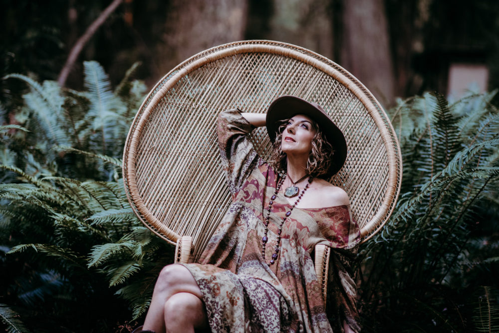 Boho woman sitting in a peacock hair in the woods