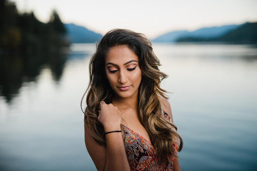 long-haired, middle-eastern woman with closed eyes stands by the ocean with a full glam makeup look for her personal branding portraits.