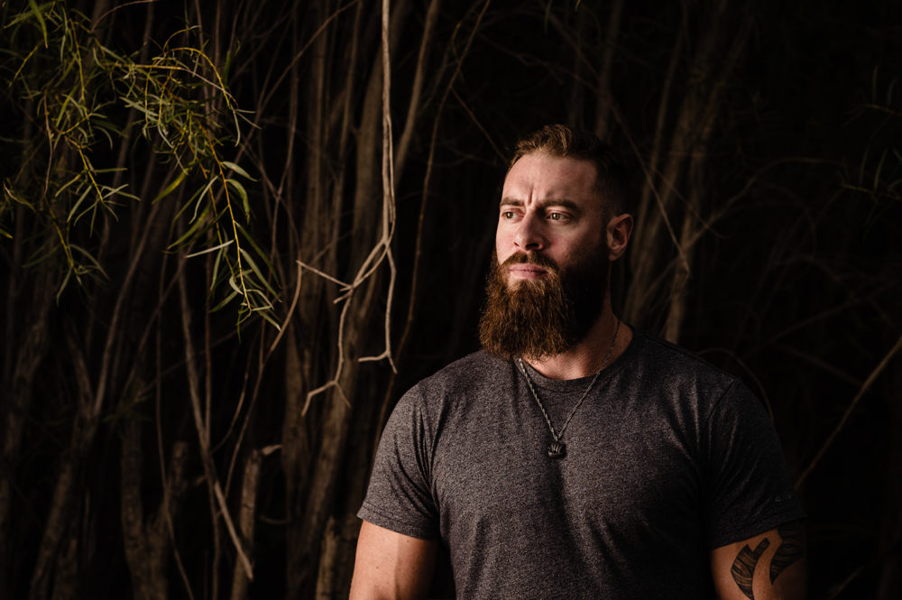 a character headshot of a young bearded guy with tattoos looking contemplative by sunshine coast headshot photographer