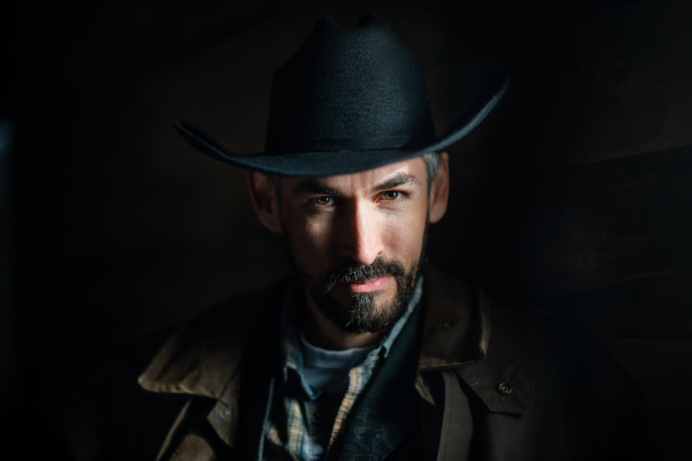 handsome cowboy with gray in his hair and beard wearing a hat and painted by light during his sunshine coast headshots